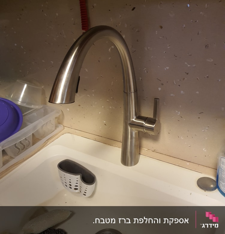 ברז נירוסטה מעל כיור מטבח עם ספוגים